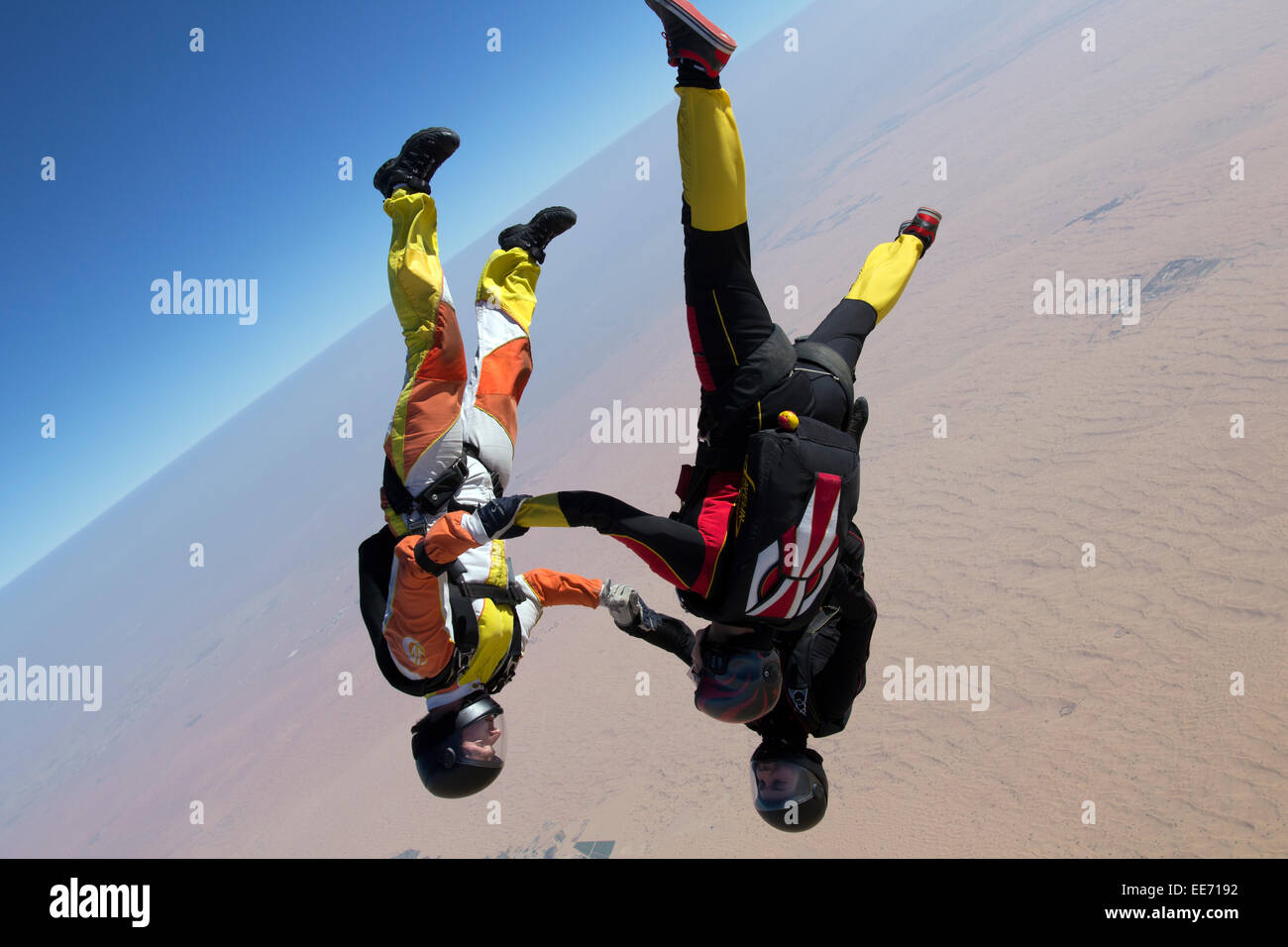 Skydiving team is holding hand together after they jumped out from a plane. Thereby they have fun and play in the blue sky. Stock Photo