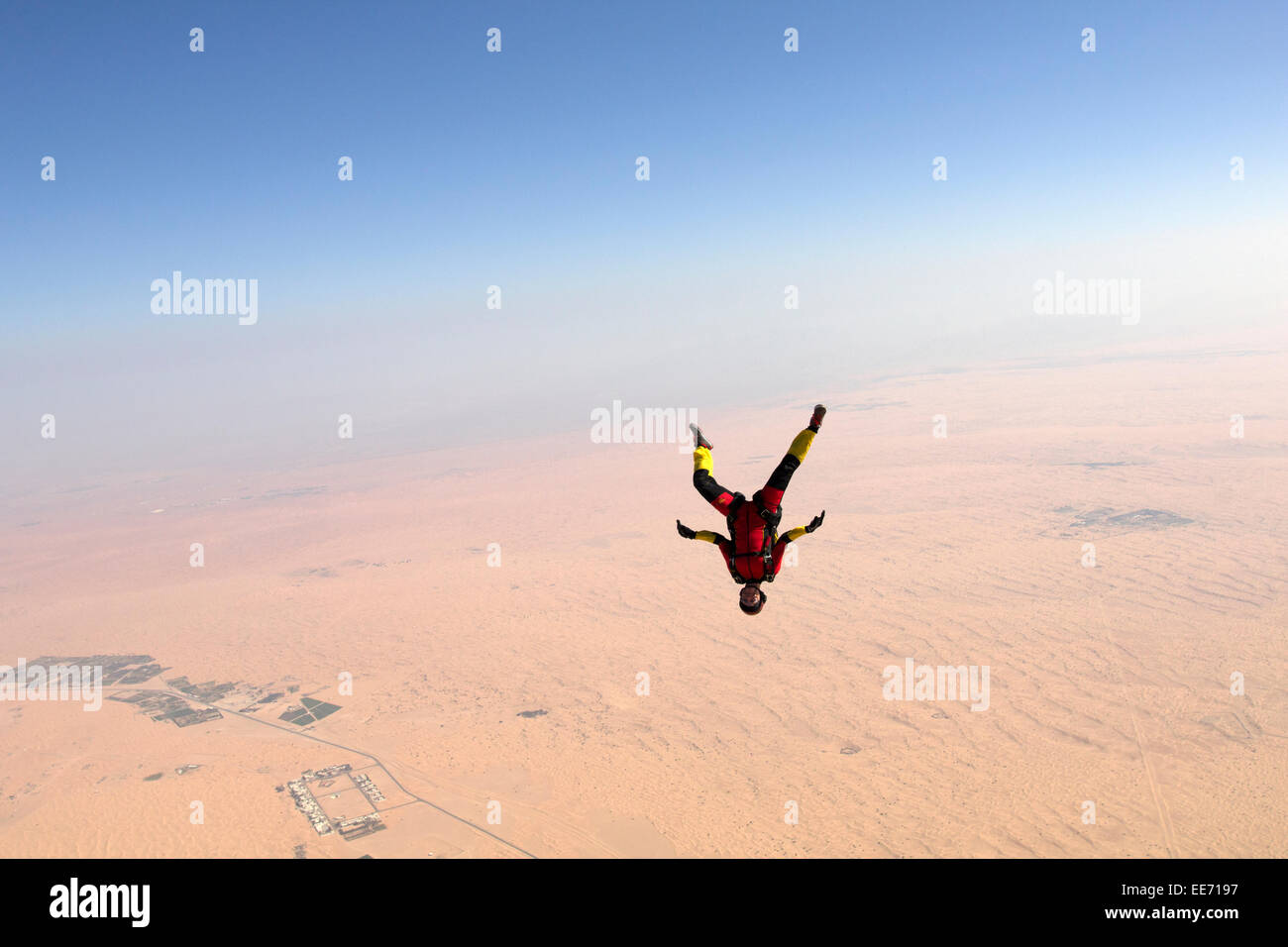Skydiver in a freefly frog headdown position is flying over a big desert area. Thereby the girl is flying with over 120mph speed Stock Photo