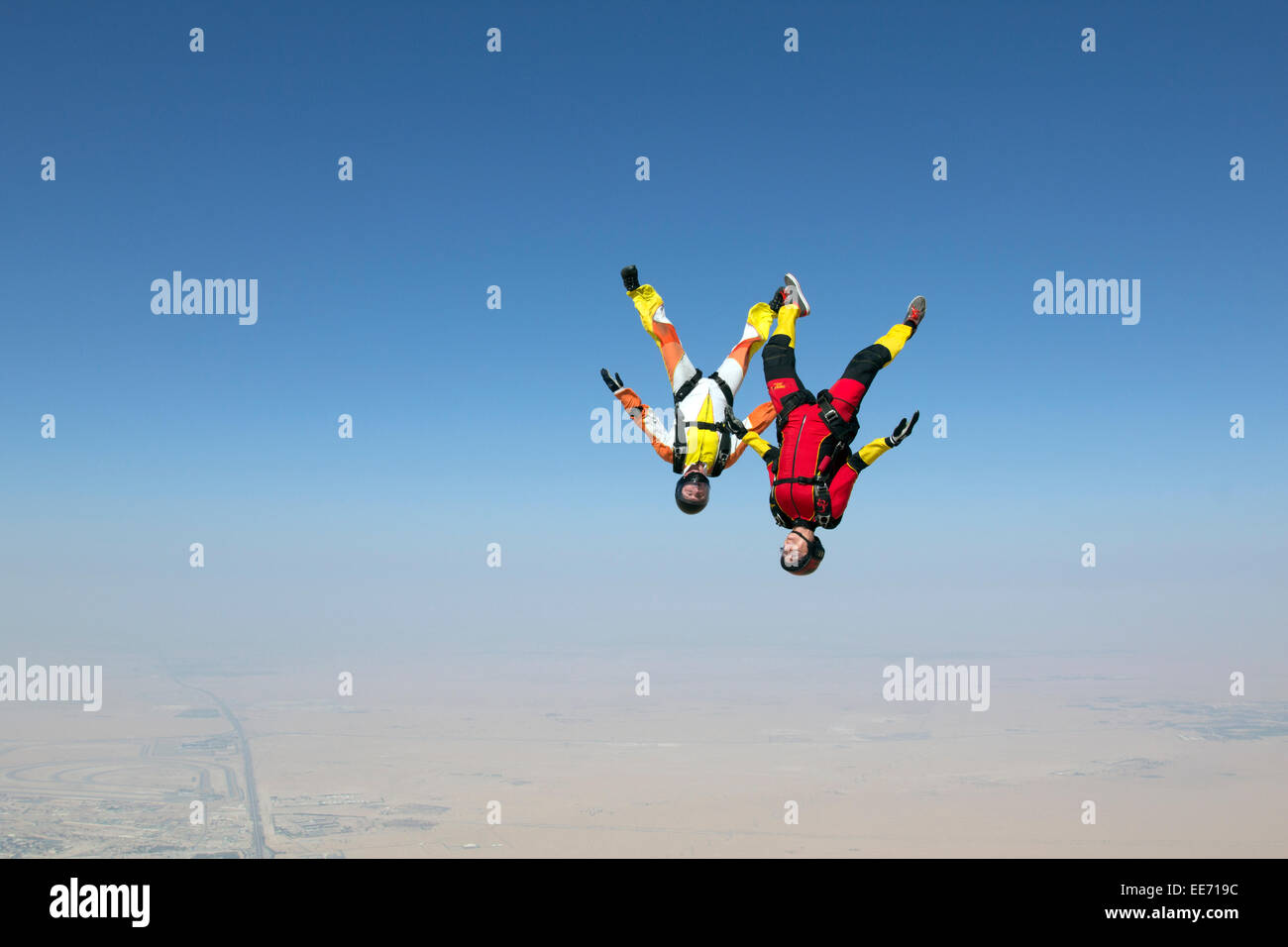 These two skydivers are training the head down flight together. The red jumper is leading with a speed over 120mph in the sky. Stock Photo