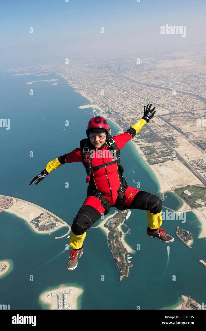 Skydiving girl is relaxed sit flying over the nice Dubai beach line with the Burj Khalifa and Burj al Arab in the background. Stock Photo