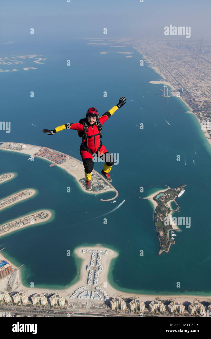 Skydiving girl is in a sit position flying over the beautiful Dubai beach shore line with the Burj al Arab in the background. Stock Photo