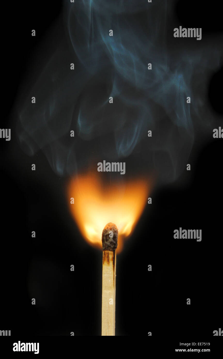 Flaming match and smoke against a dark background Stock Photo