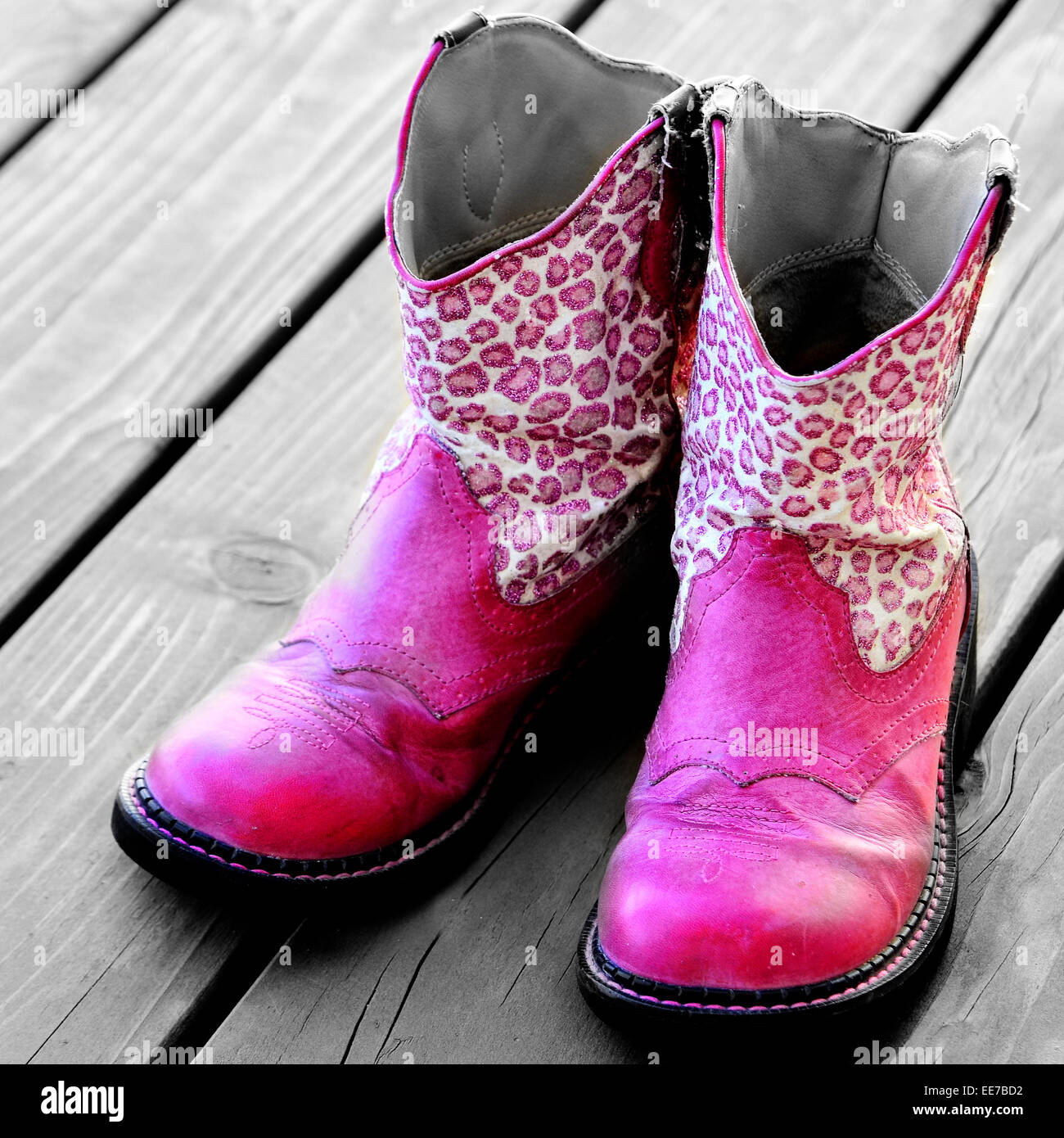 Detail of pink cowgirl cowboy boots on wood deck for a girl Stock Photo