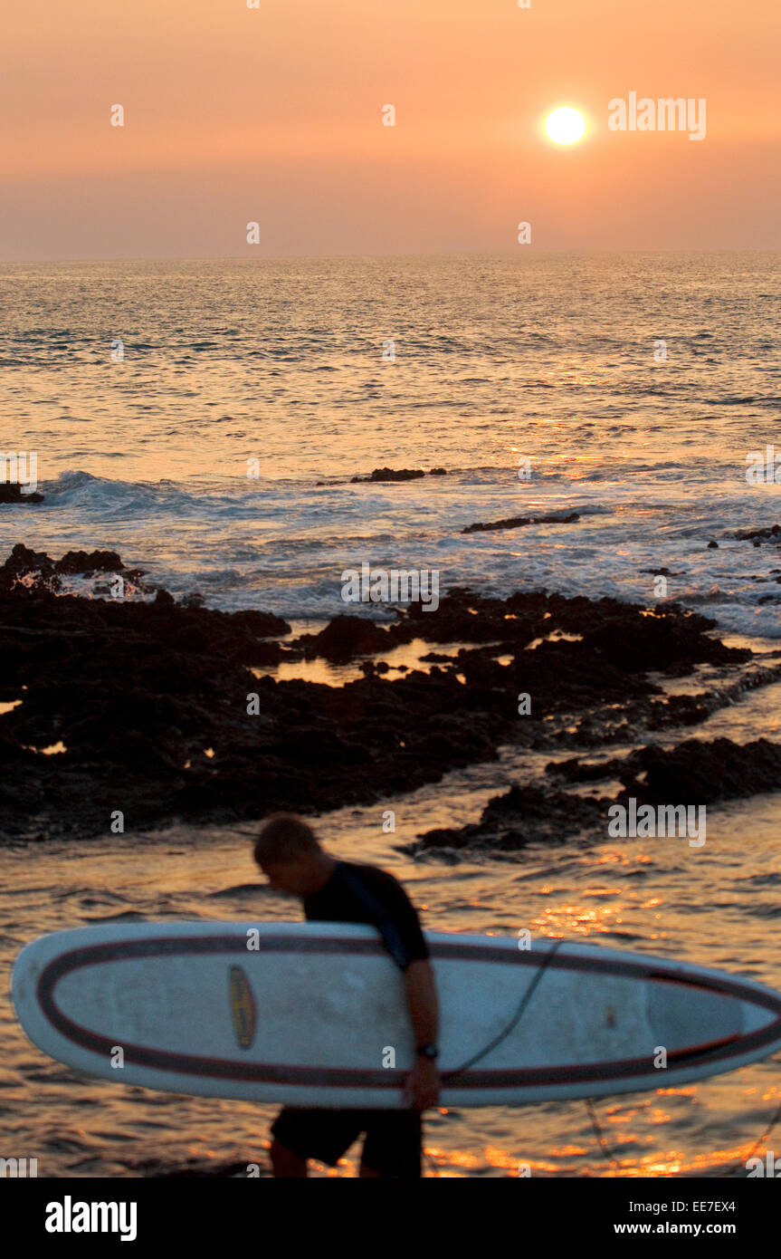 Surfer at sunset on the beach in Waikoloa. Big Island. USA. Surfers in the coral and lava flank Anaeho'omalu Bay in Hawaii. Waik Stock Photo