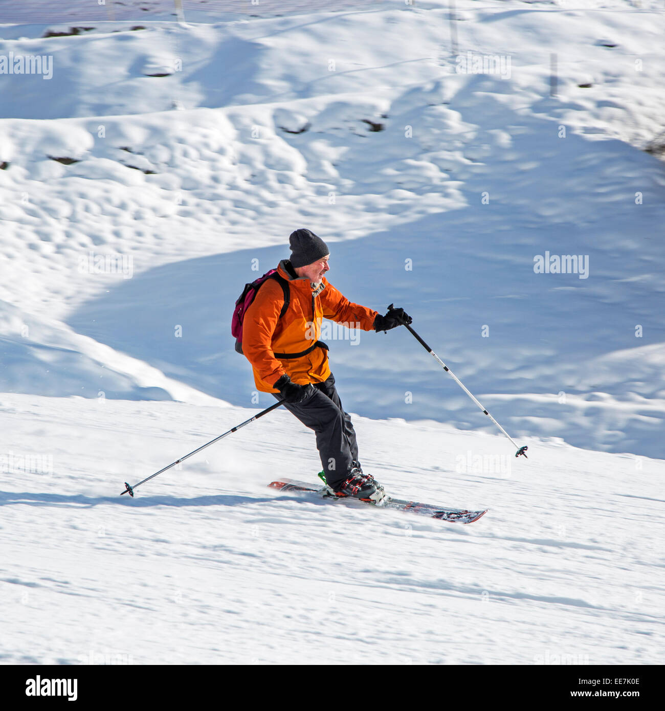 Skier with rucksack skiing down ski slope in winter sports resort in the Alps Stock Photo