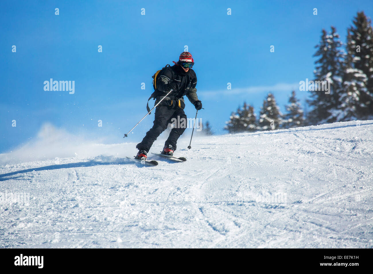 Skier with backpack skiing down ski slope in winter sports resort in the Alps Stock Photo