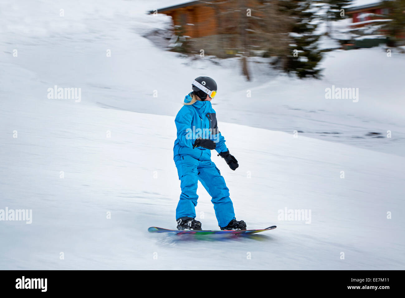 Young snowboarder wearing ski helmet descending ski slope in winter sports resort in the Alps Stock Photo