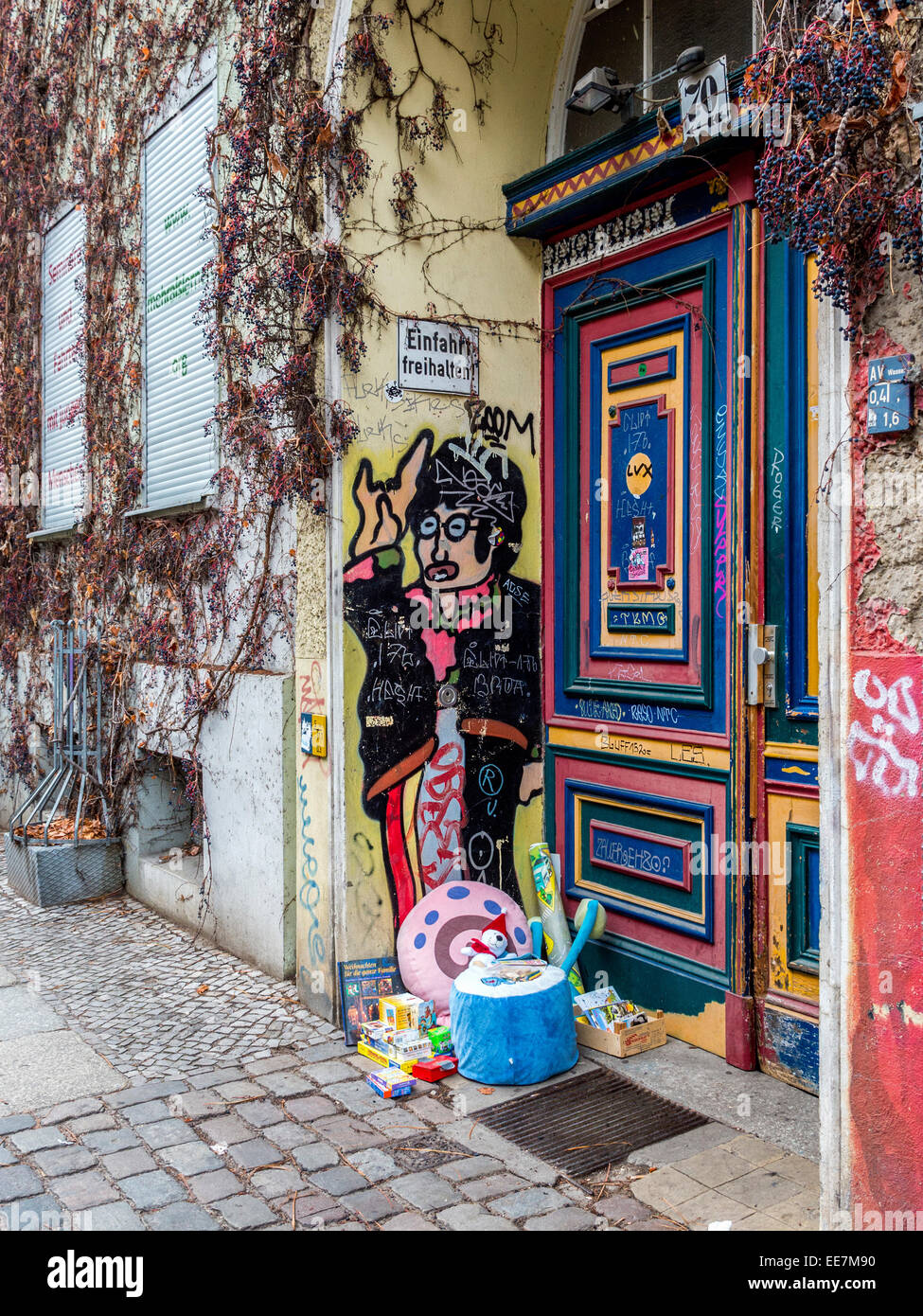 Entrance to apartment building with colorful street art and pile of donated toys, Auguststrasse, Mitte, Berlin Stock Photo