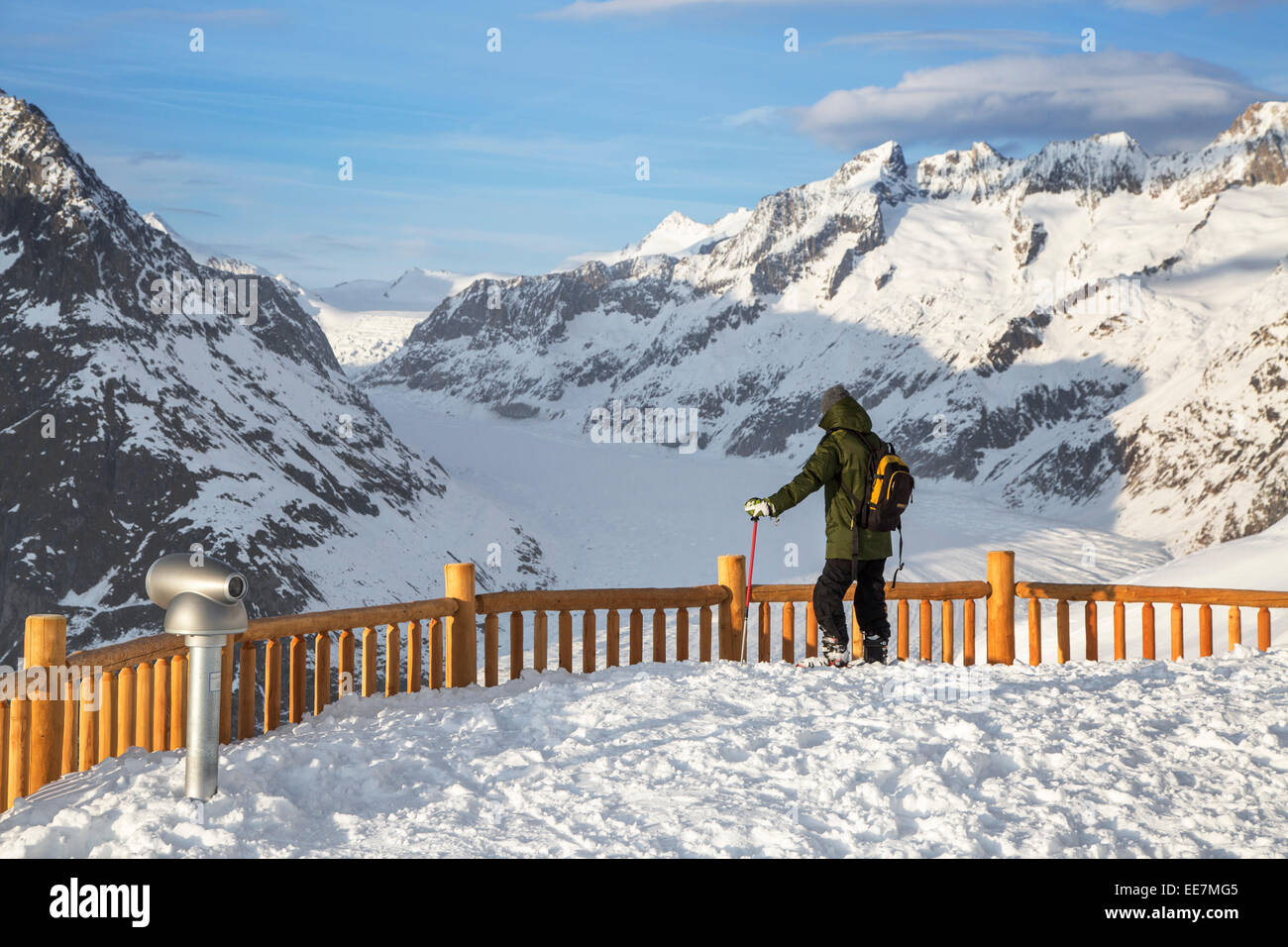 Tourist in the snow looking over the mountains in winter surrounding the Swiss Aletsch Glacier, largest in the Alps, Switzerland Stock Photo