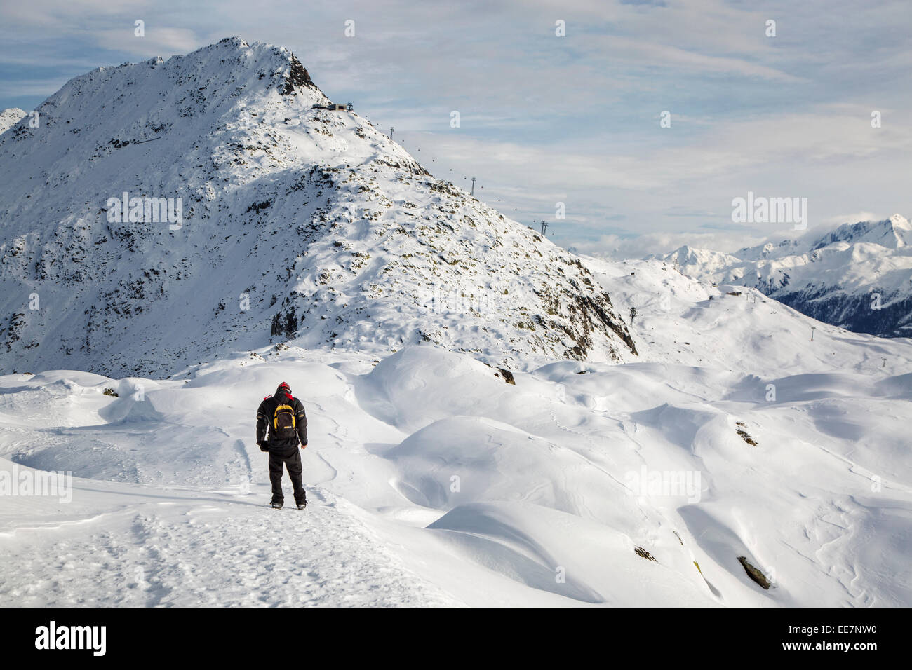 Tourist in the snow looking over the mountains in winter surrounding the Swiss Aletsch Glacier in the Alps, Switzerland Stock Photo