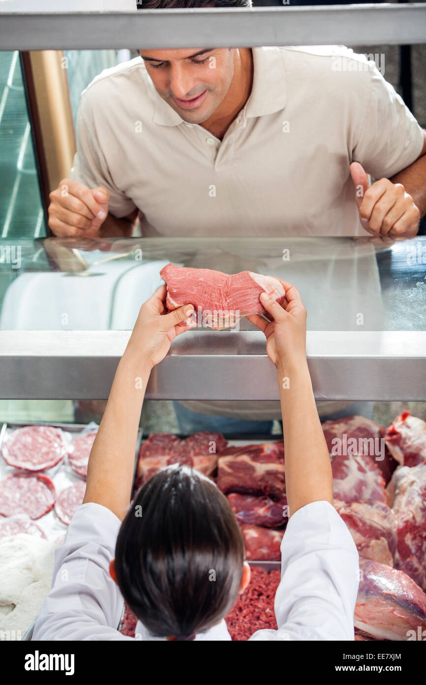 Butcher Showing Fresh Red Meat To Customer Stock Photo