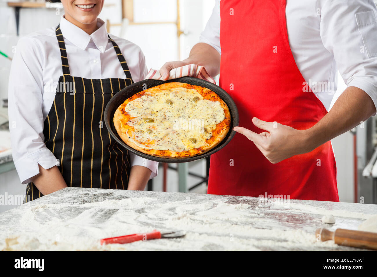 Chefs Presenting Delicious Pizza At Commercial Kitchen Stock Photo