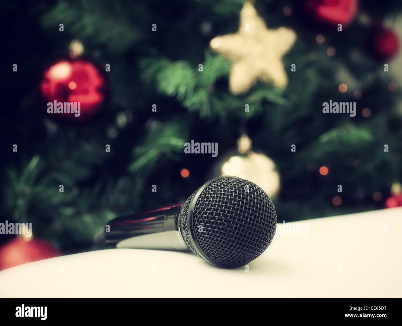Black microphone on white leather sofa near the Christmas tree. Concept of Christmas song music. Stock Photo