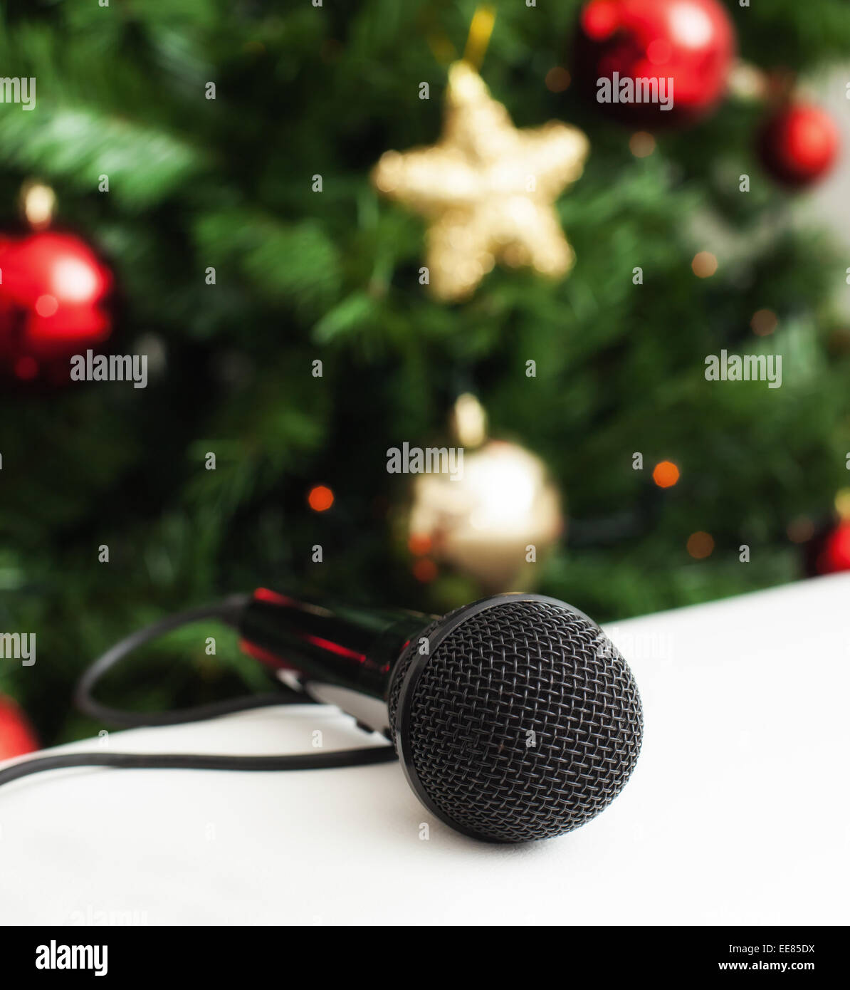 Black microphone on white leather sofa near the Christmas tree. Concept of Christmas song music. Stock Photo