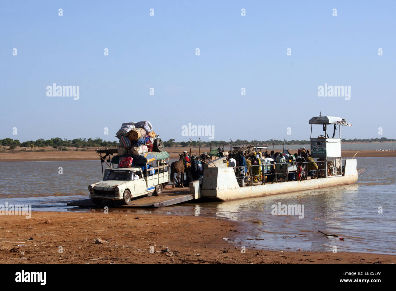 A heavily-loaded truck drives off the ferry crossing the River Bani near Djenne, Mali Stock Photo