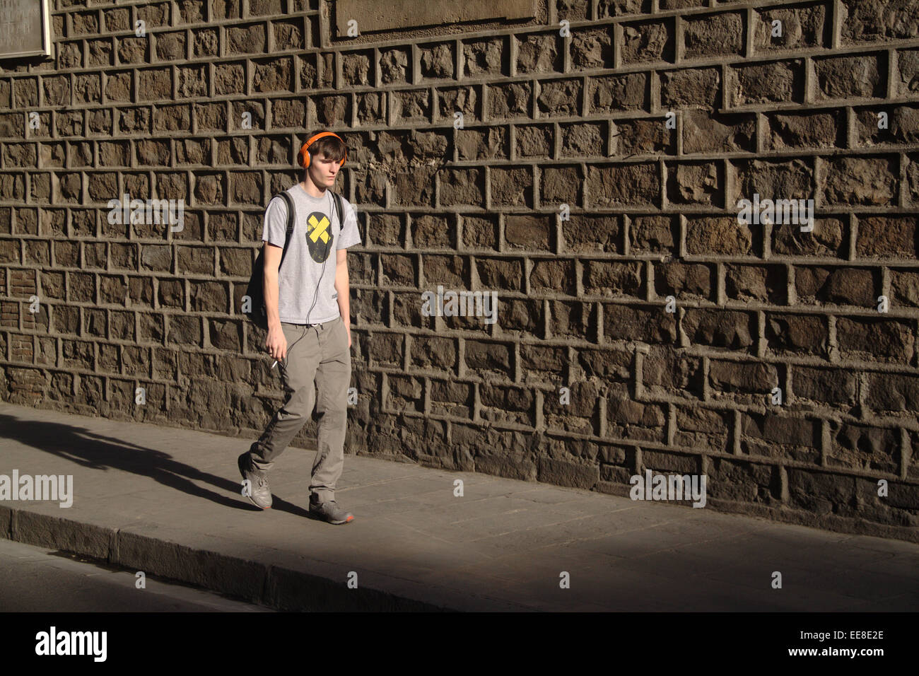 Boy walking along the street, wearing headphones and holding cigarette, in Carrer del Carme, El Raval, Barcelona. Stock Photo