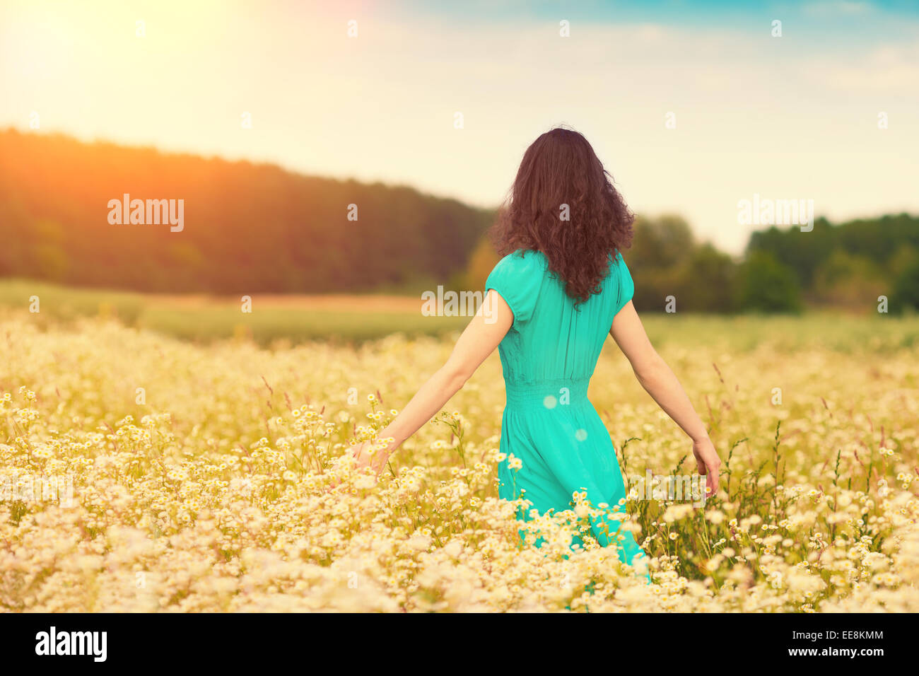 Young happy girl walking on the flower meadow Stock Photo