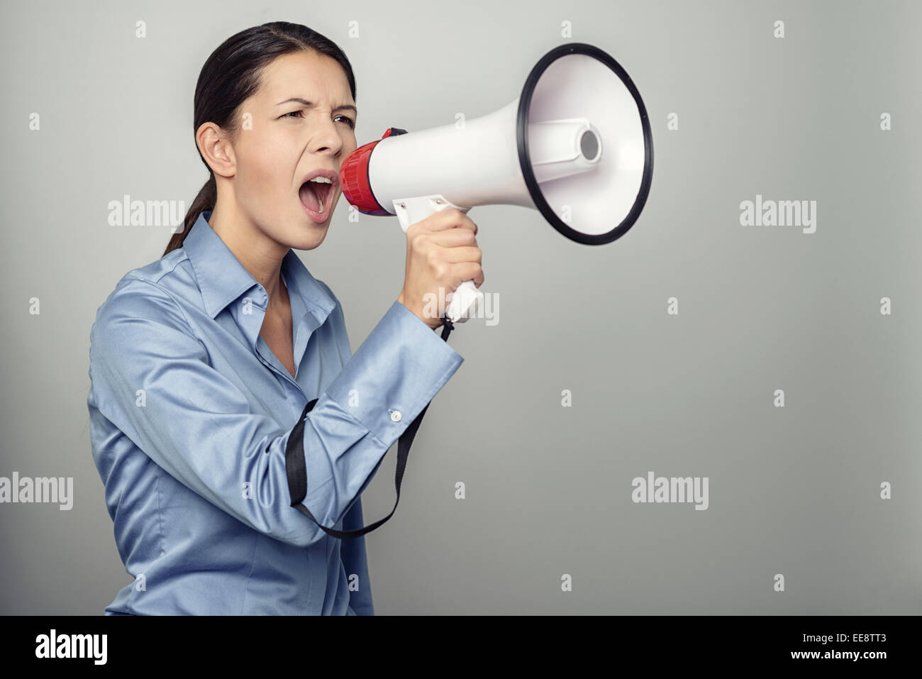 Woman speaking over a megaphone as she makes a public address, participates in a protest or organises a rally or promotion Stock Photo