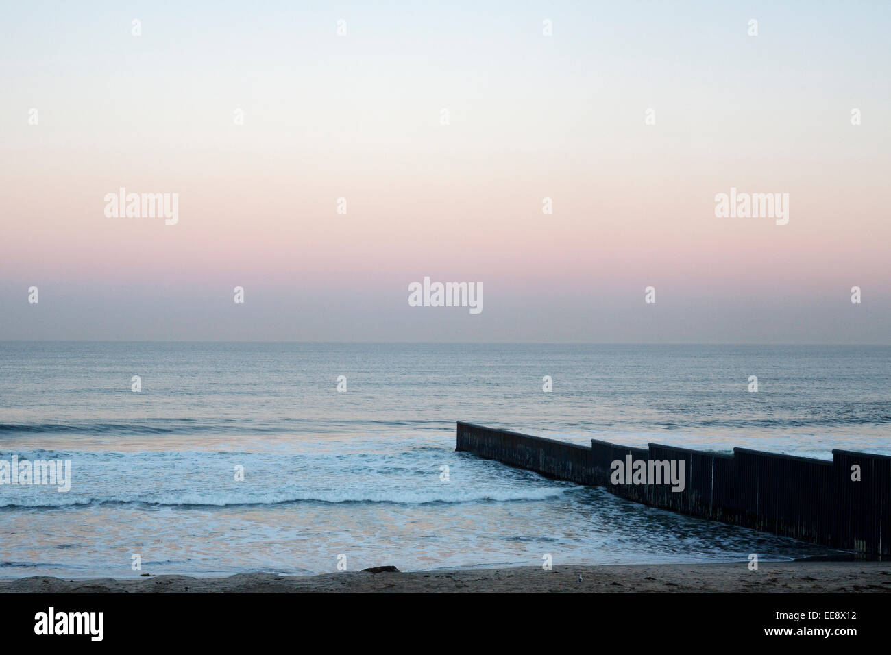 Sunrise at Tijuana beach in Mexico, showing the the US - Mexican border fence running into the Pacific Ocean. Stock Photo