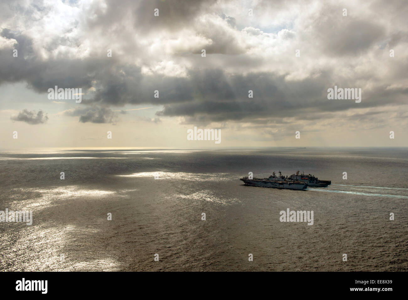 US Navy amphibious assault ship USS Makin Island and the amphibious dock landing ship USS Comstock during operations on a cloudy day January 14, 2015 in the Andaman Sea. Stock Photo