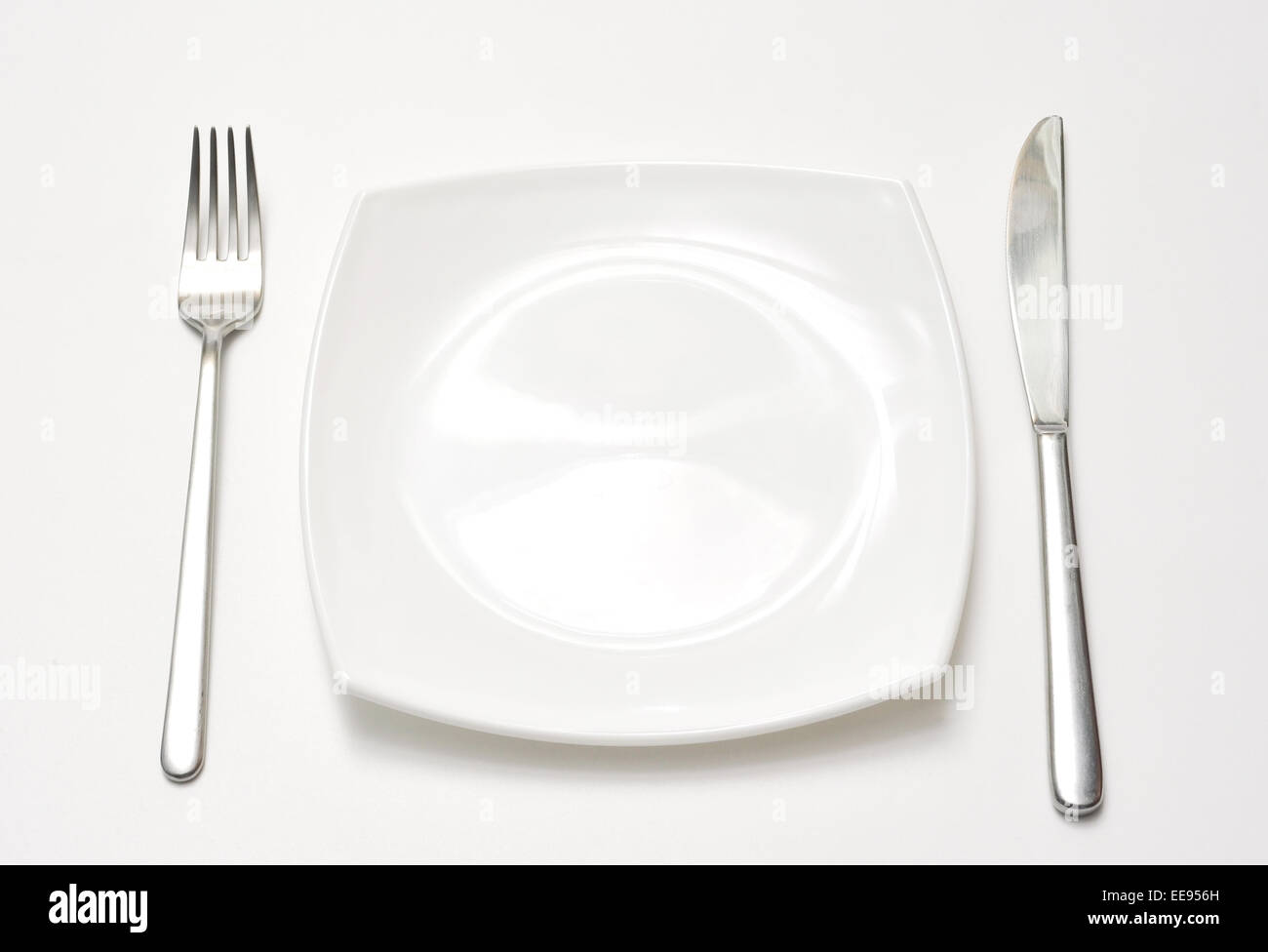 Empty plate with fork and knife over white background Stock Photo - Alamy