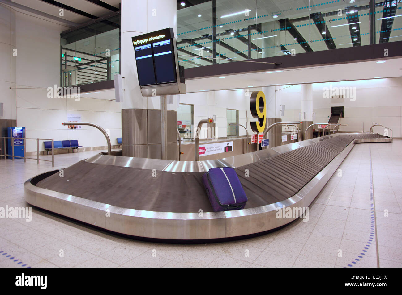 A single bag is left rotating on a baggage reclaim conveyor in a deserted baggage reclaim hall. Gatwick North Terminal Stock Photo