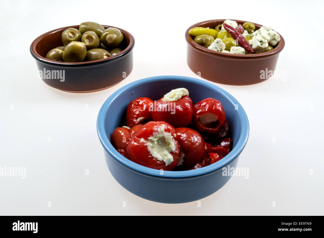 Three rustic bowls filled with antipasti on light background Stock