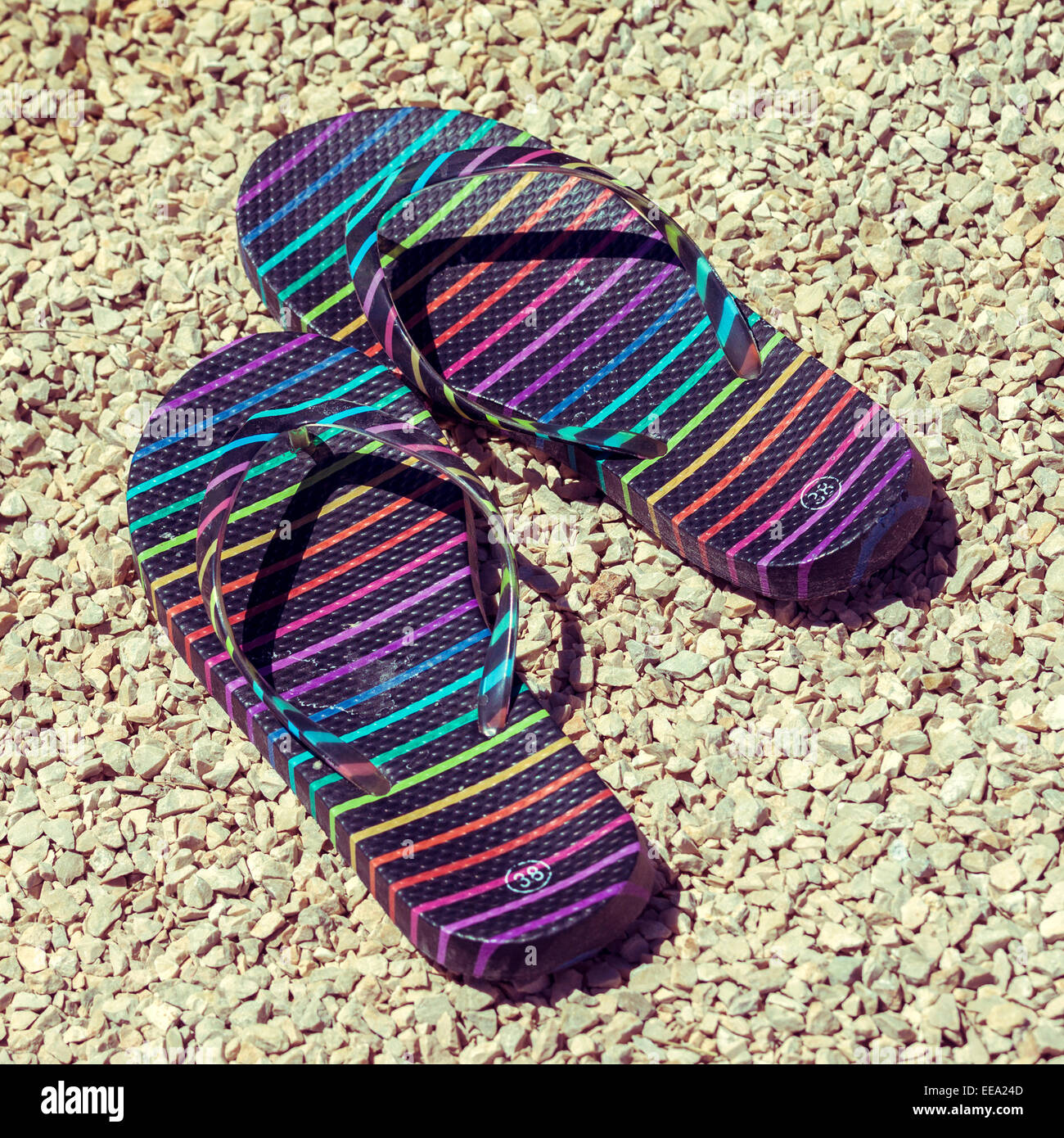Pair of flip flops on stony beach. Picture with colorized retro