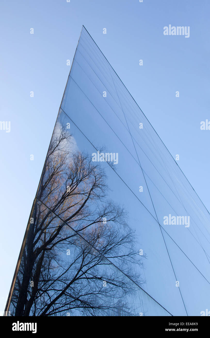 glass facade of modern office building and reflection of trees and blue ...
