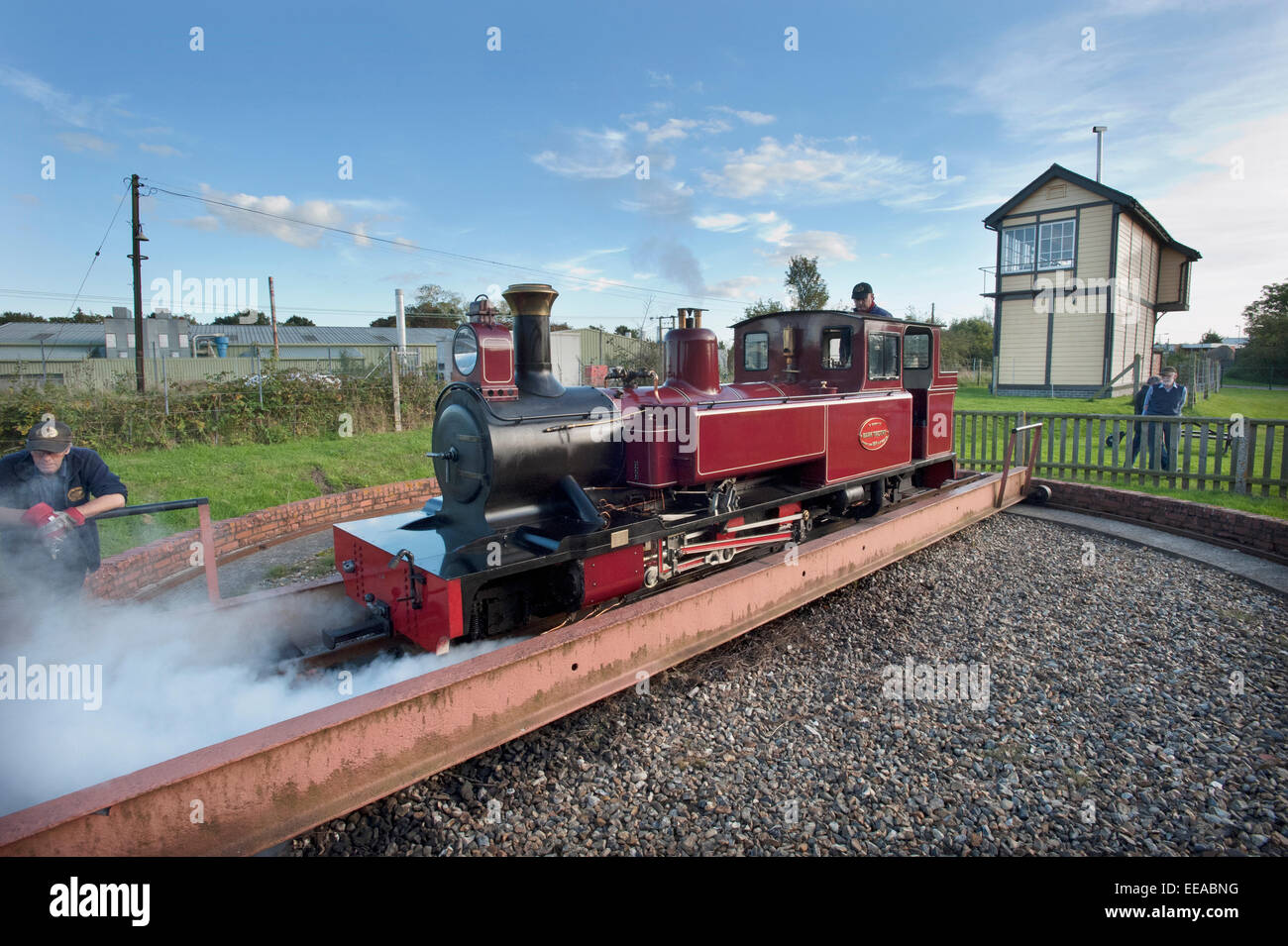 Picture by Roger Bamber : 05 October 2014 : The driver uses his injectors to move off the Turntable at Wroxham station terminus in his 15-Inch narrow gauge steam locomotive "Mark Timothy" before it runs round its train on The Bure Valley Railway to return to Aylsham on the 9 miles between Aylsham and Wroxham, near Norwich, Norfolk. Behind is the giant Network Rail Wroxham main line Signalbox. Stock Photo