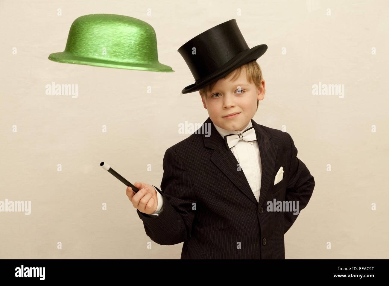 young boy dressed up as a magician making a hat float in midair Stock