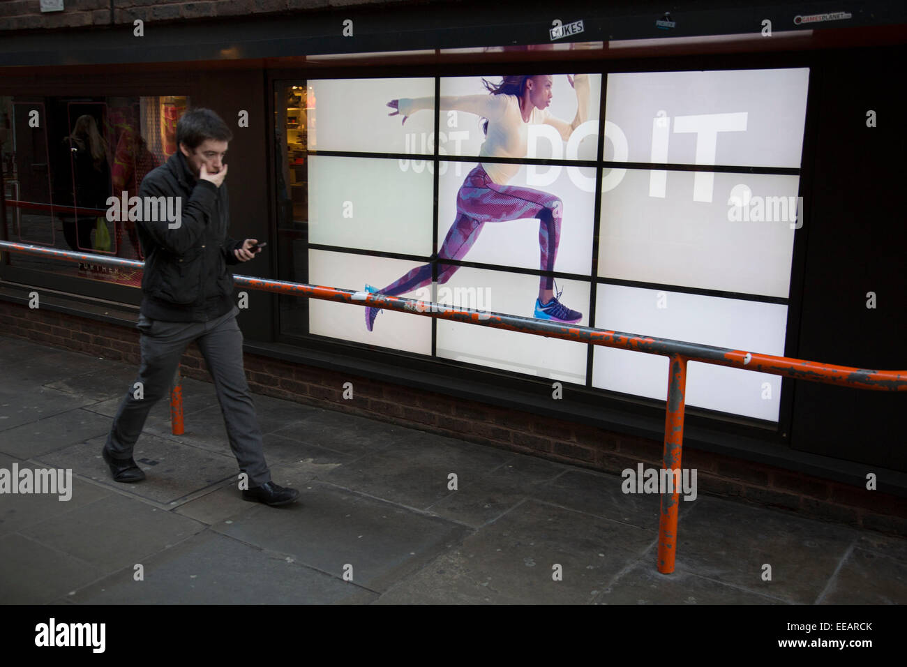 Nike advertising runner runs along a barrier near unsuspecting people. The  video advert with the slogan 'Just Do It" with a woman running across the  screen makes for an optical illusion of