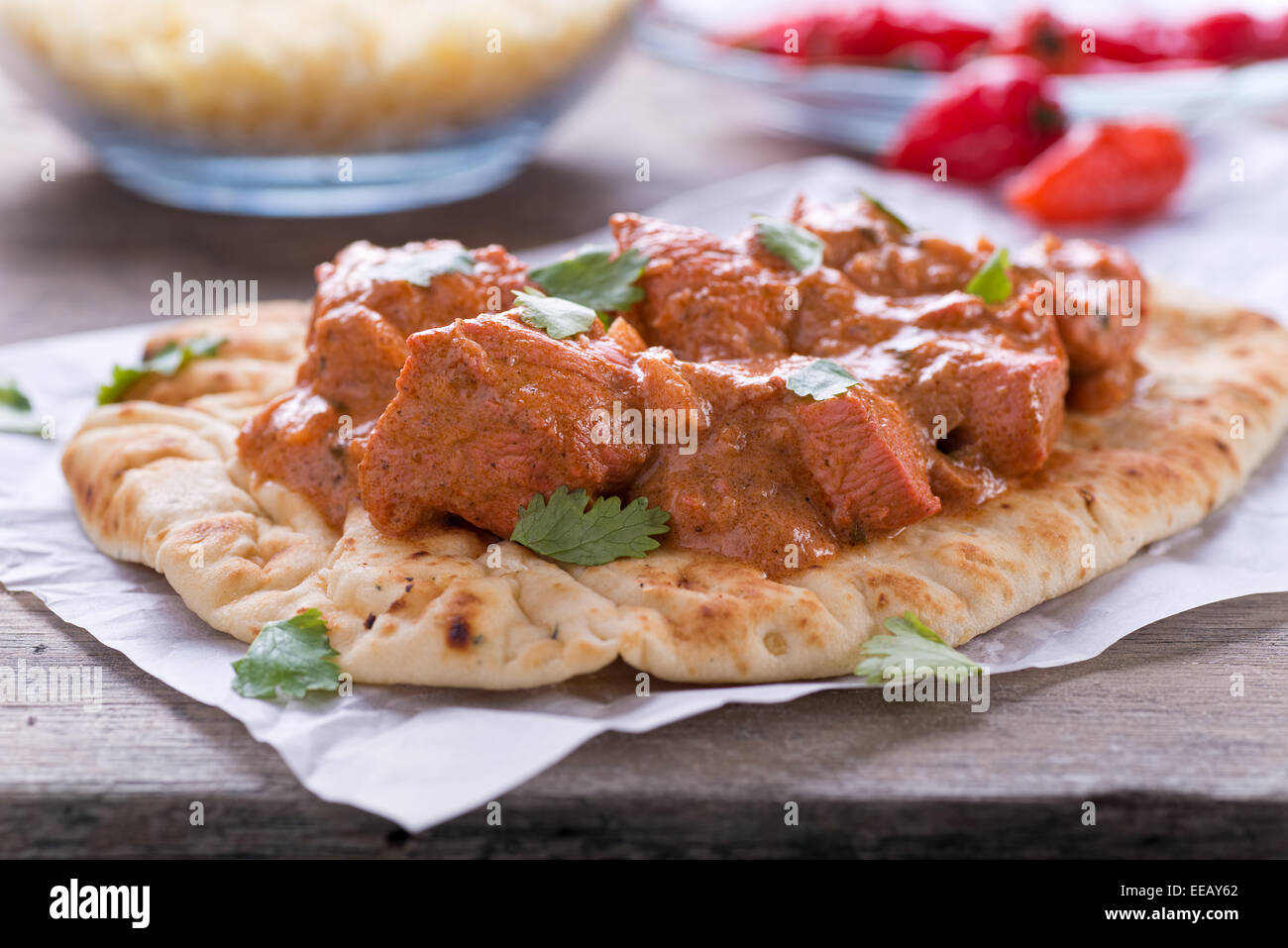 A delicious butter chicken curry served on naan bread with saffron basmati rice. Stock Photo