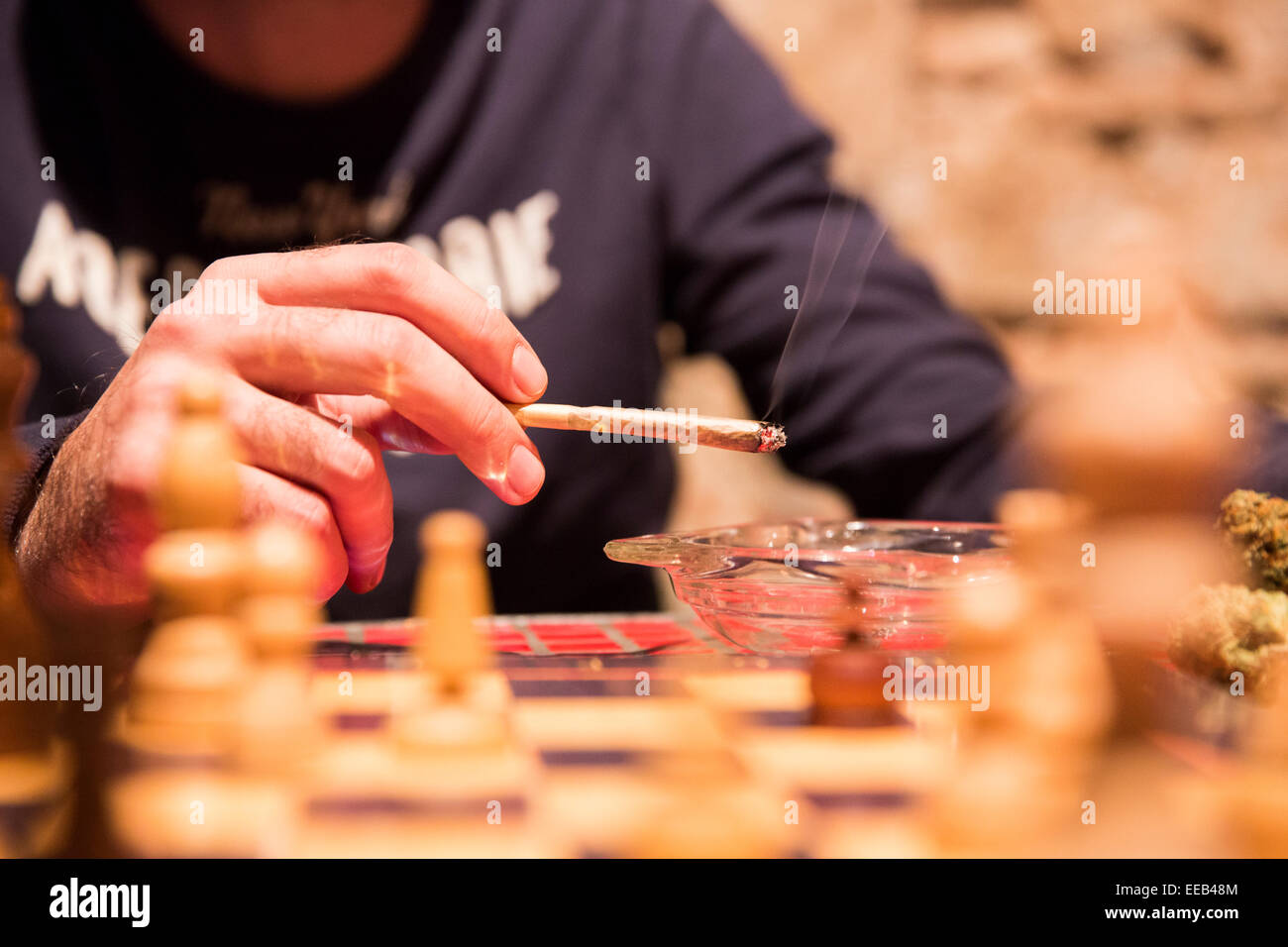 A customer smokes a marijuana cigarette as he plays a round of chess at