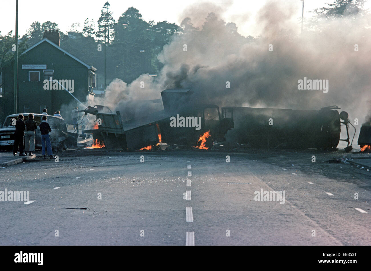 BELFAST, NORTHERN IRELAND - AUGUST 1976. Burning Hijacked Vehicles during Riots on The Falls Road, West Belfast during The Troubles, Northern Ireland. Stock Photo