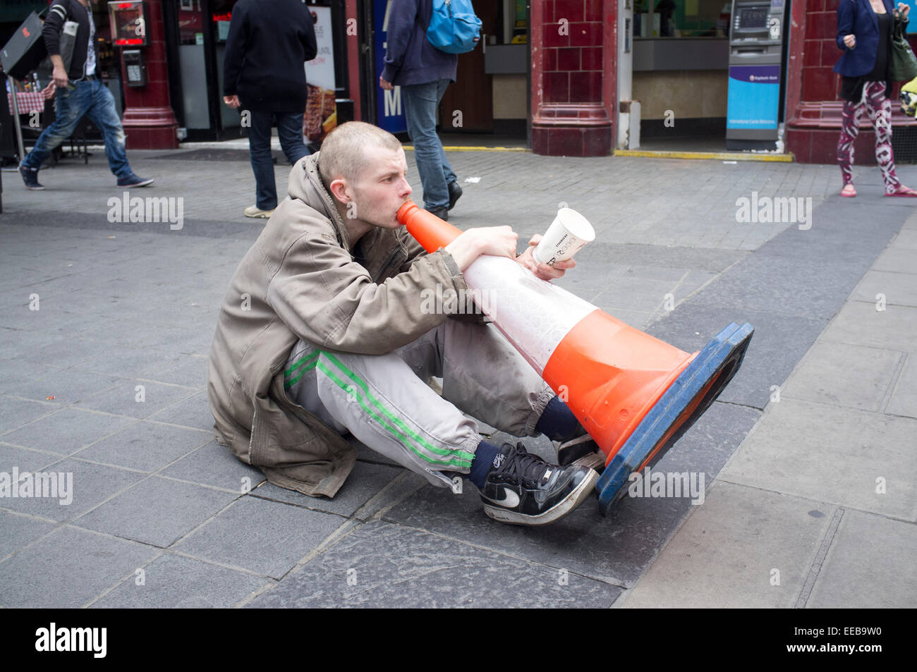 Homeless male playing music on a street cone outside Oxford Circus Station in London's West End Stock Photo