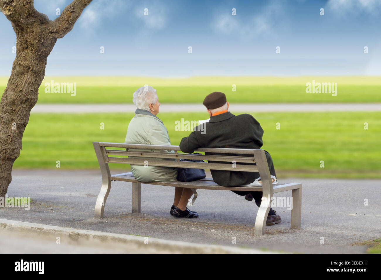 Senior Couple Sitting On The Park Bench Stock Photo - Alamy