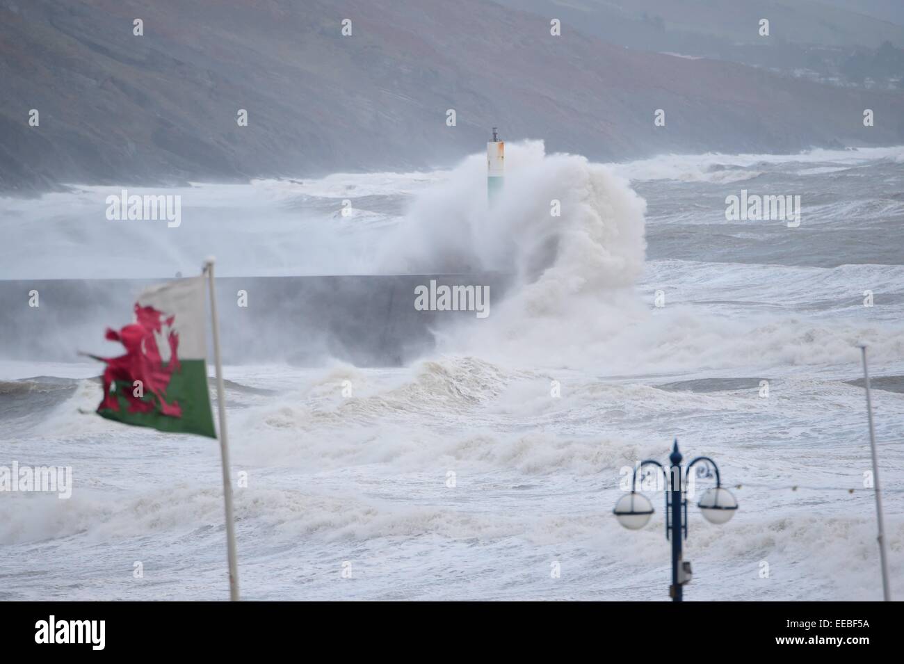 Aberystwyth, Wales, UK. 15th January, 2015. UK Weather: A battered and torn welsh flag flies as gale force winds and stormy seas continue to batter the seafront  in Aberystwyth Wales.   Flood warnings are in place for many rivers in mid and north wales.  with severe  gale force winds gusting up to 70mph in places making for "tricky travel conditions”. Stock Photo