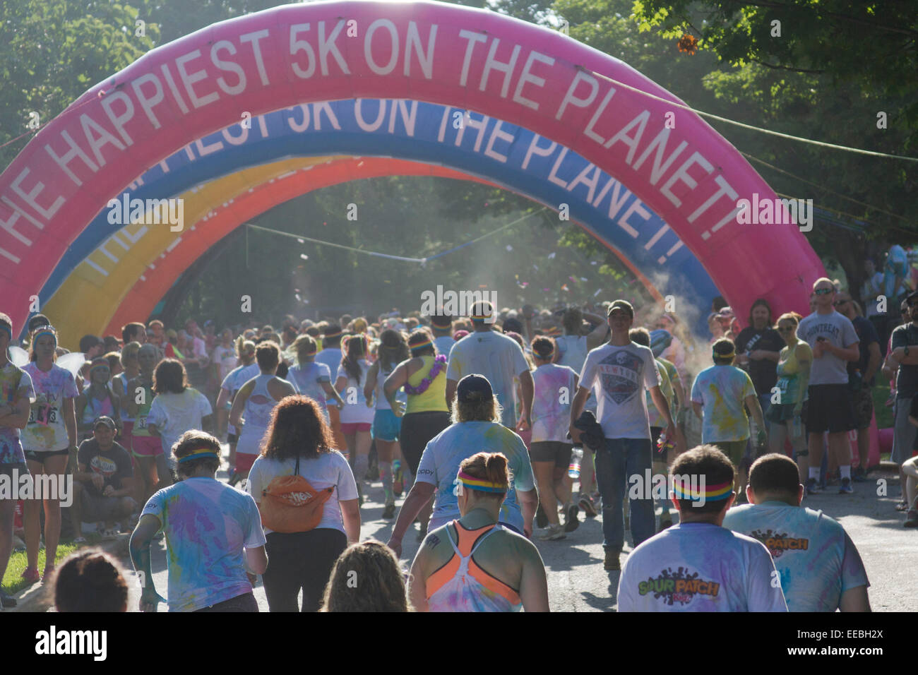 Runners splattered with colorful dyes approach the finish line in the the happy Asheville 5K Color Run Stock Photo
