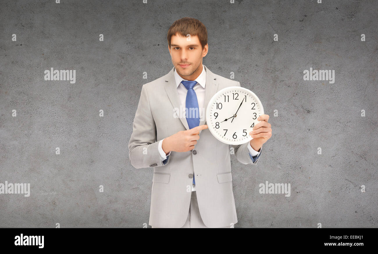 handsome businessman pointing finger to wall clock Stock Photo