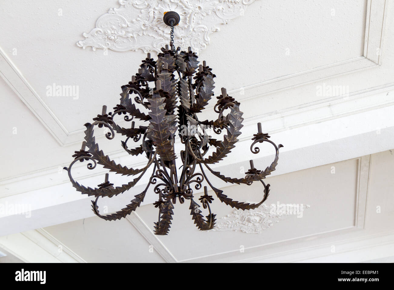 Vintage black candle holding chandelier hanging from white ceiling