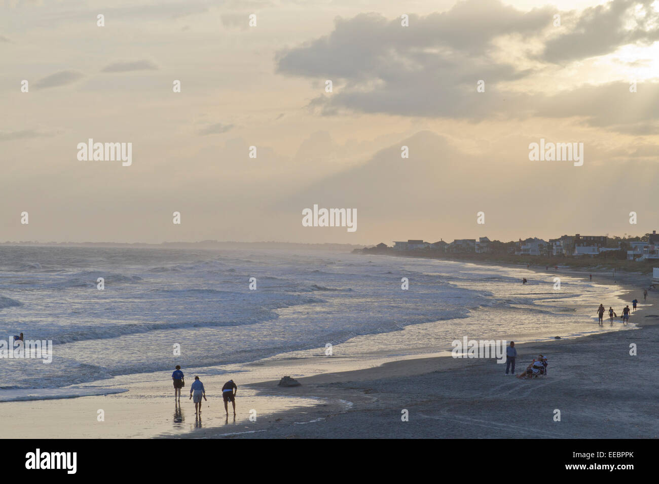 Relaxed people wander the beach and play in the ocean at twilight Stock Photo