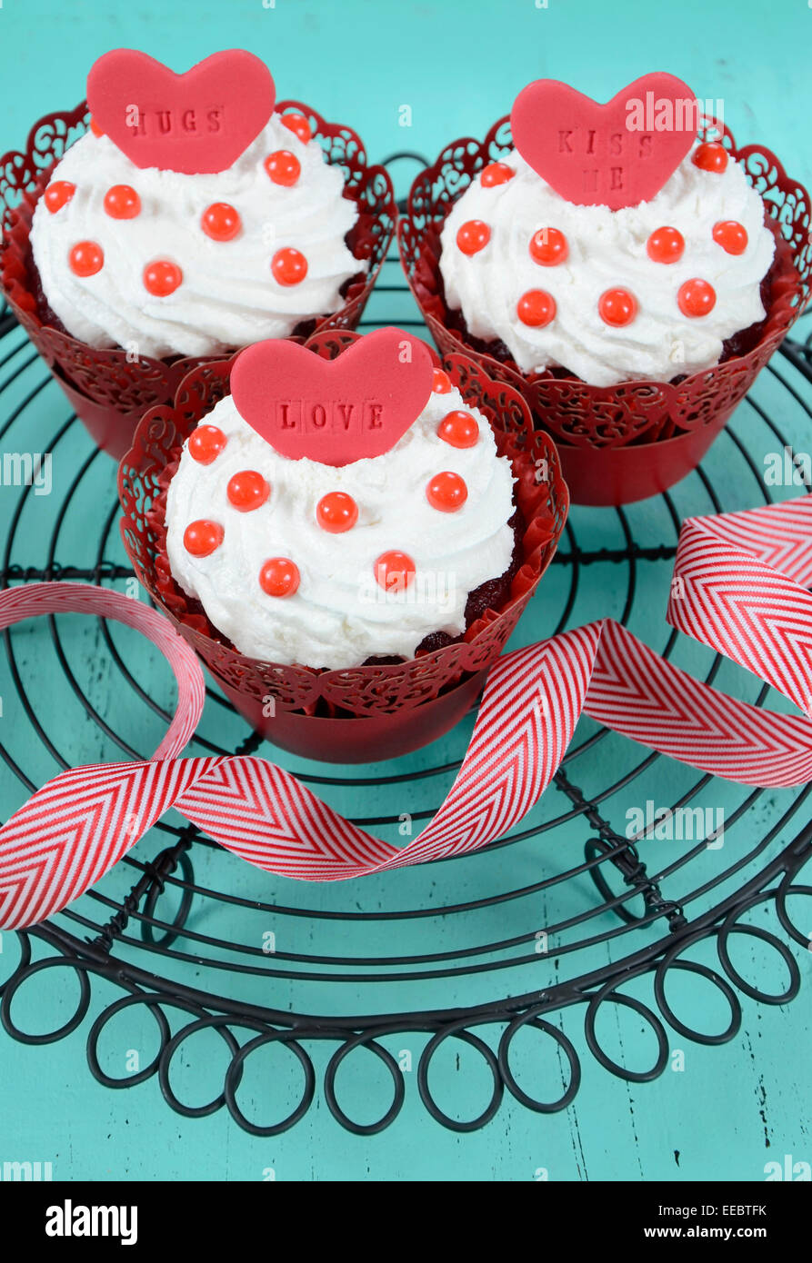Happy Valentine red velvet cupcakes with love messages on vintage baking  rack on green teal blue sixties style vintage wood Stock Photo - Alamy