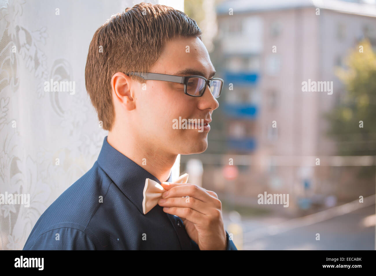 Portrait of young groom tying bow tie while getting ready for wedding ... - Tying A Tie For A Groom Party