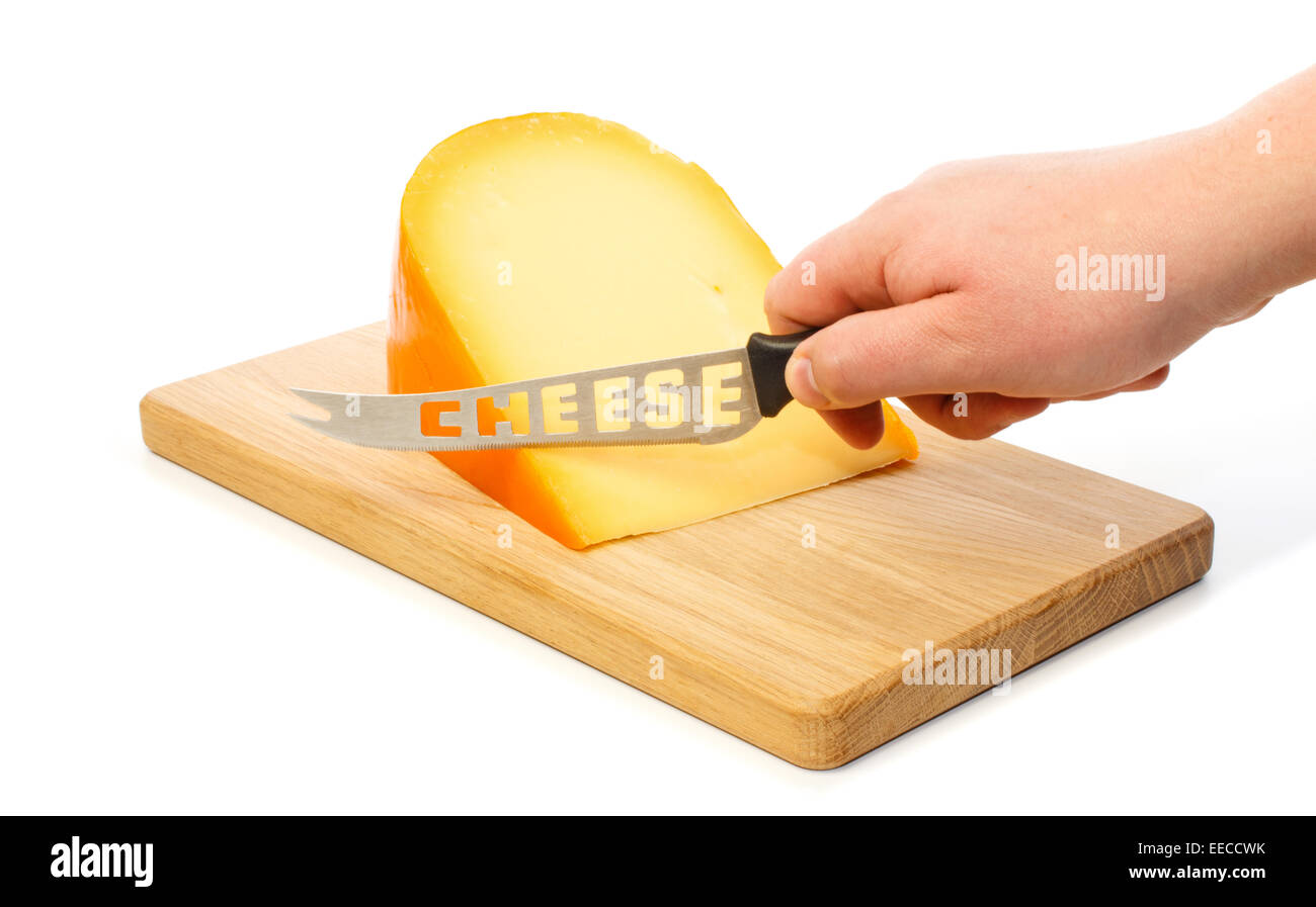 Hand cuts with cheese knife the Dutch Gouda cheese on a cutting board Stock Photo
