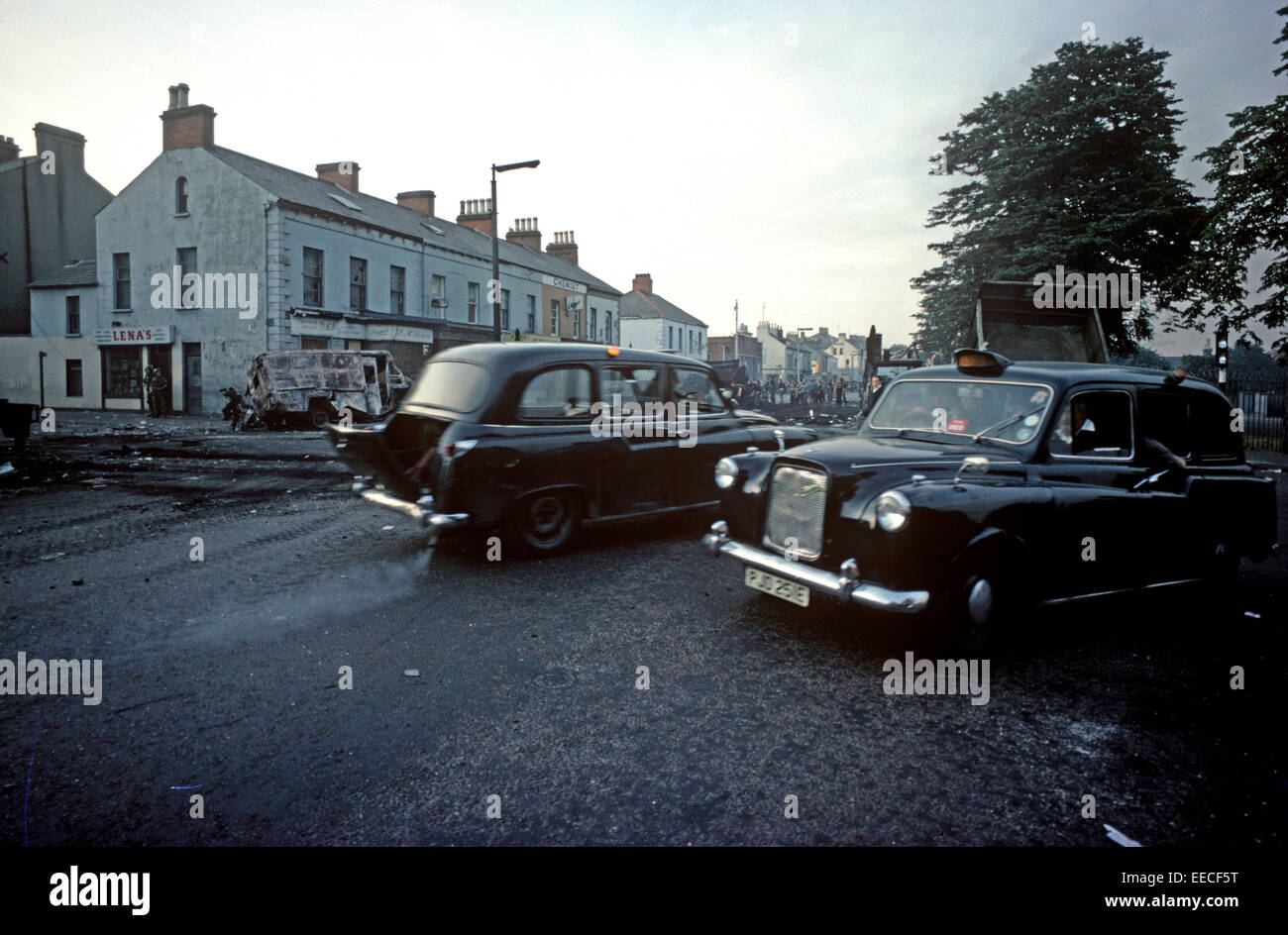 BELFAST, NORTHERN IRELAND - AUGUST 1976. Black Taxis, the Peoples Taxis, operaring on the falls Road, West Belfast after a night of Riots during The Troubles, Northern Ireland. Stock Photo