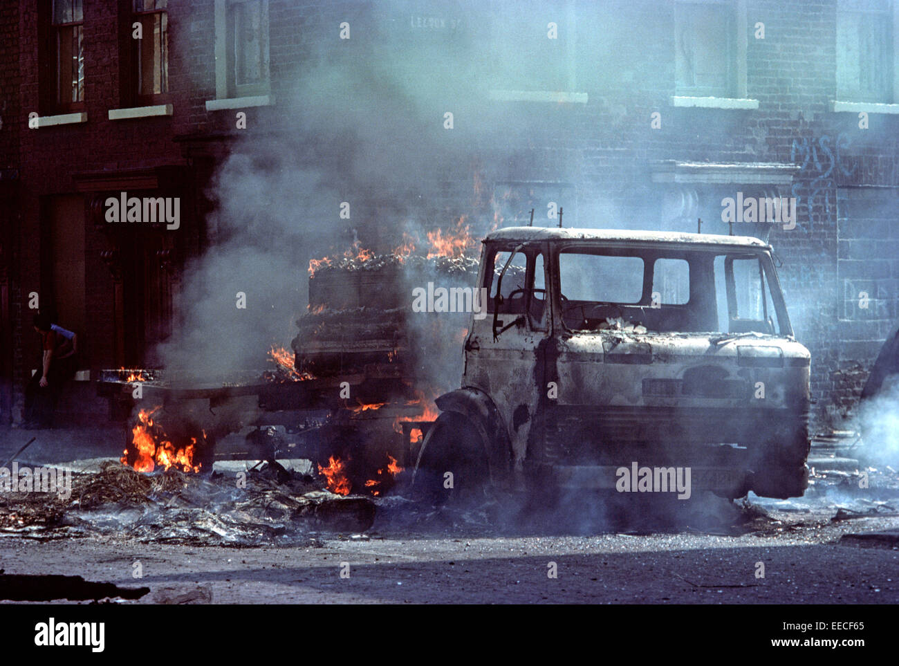 BELFAST, NORTHERN IRELAND - AUGUST 1976. Burning Hijacked Vehicles during Riots on The Falls Road, West Belfast during The Troubles, Northern Ireland. Stock Photo