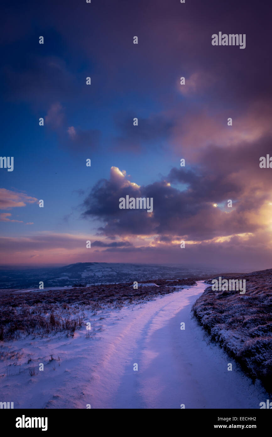 Snowy path in pretty pink light in the snow at dawn on Ilkley Moor in the Yorkshire countryside, UK Stock Photo