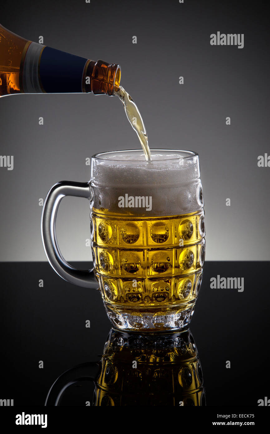 Beer poured from a bottle on the dark background Stock Photo