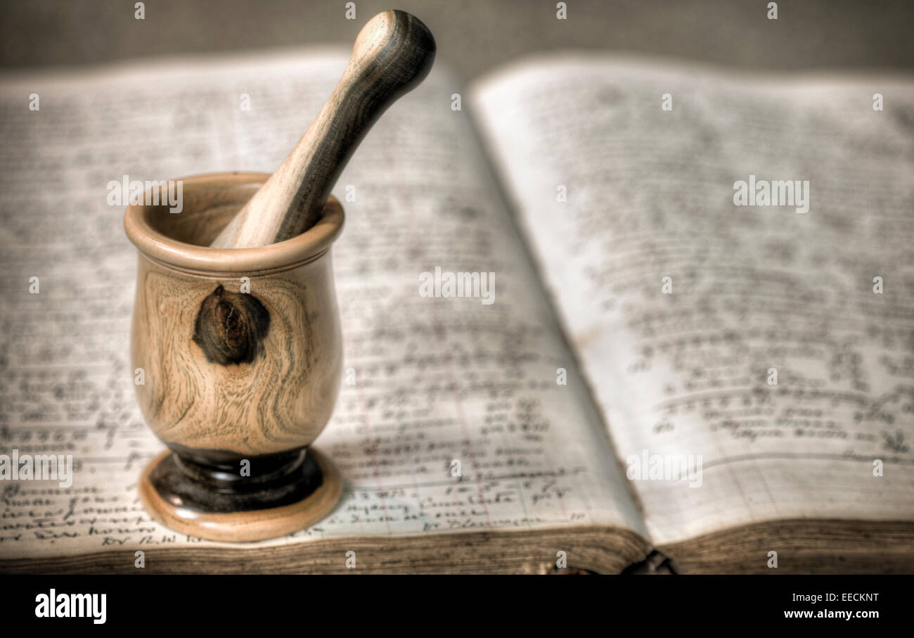 Antique wooden mortar and pestle on top of old pharmacy book Stock